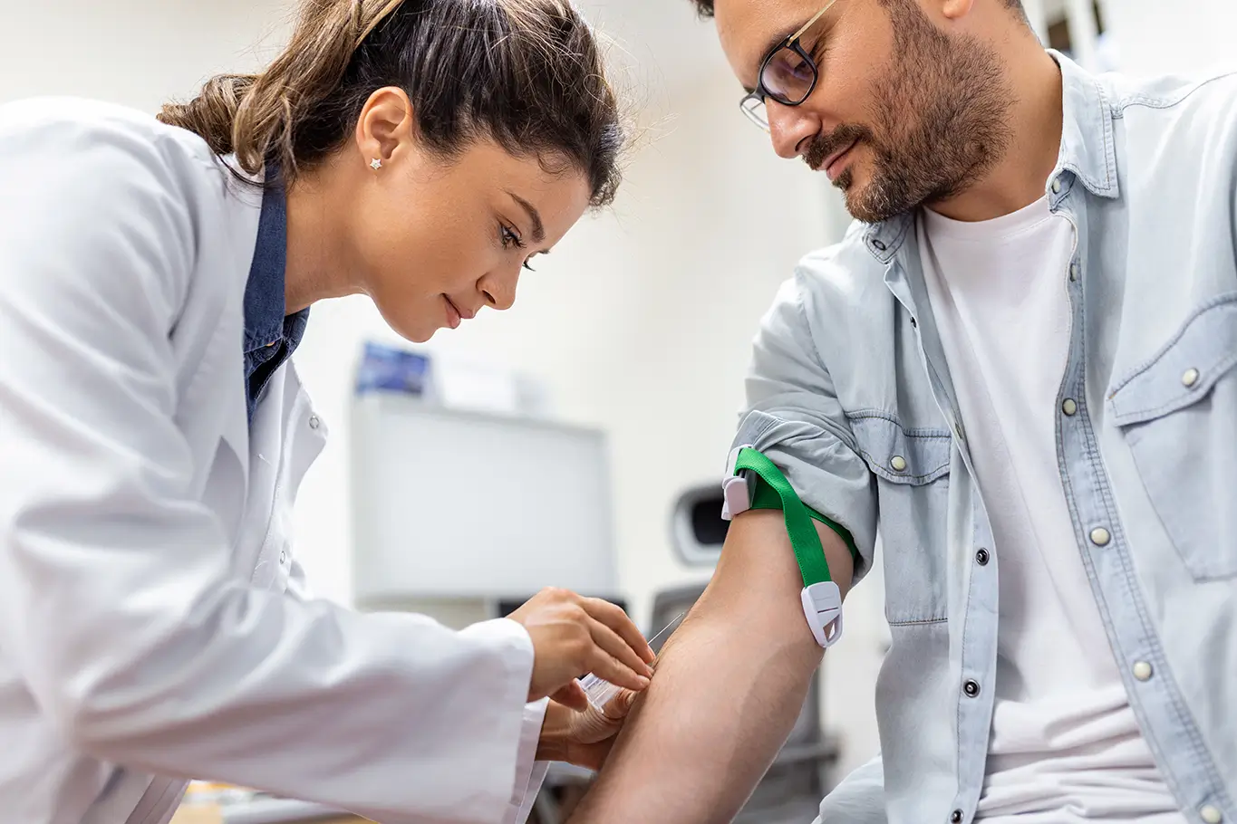 A healthcare professional checks the blood pressure of a man in a medical office.