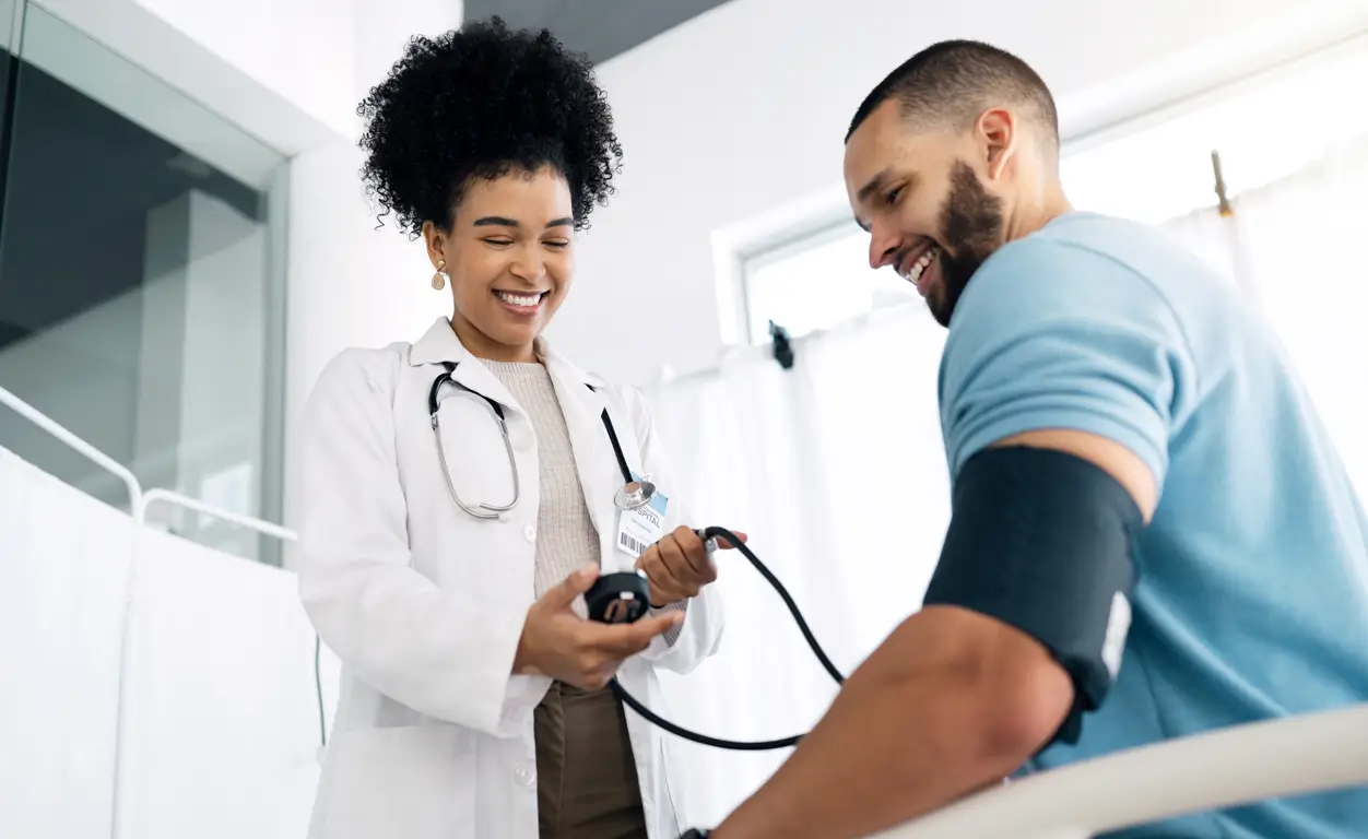 A healthcare professional checks a patient's blood pressure with a cuff and monitor in a medical office.