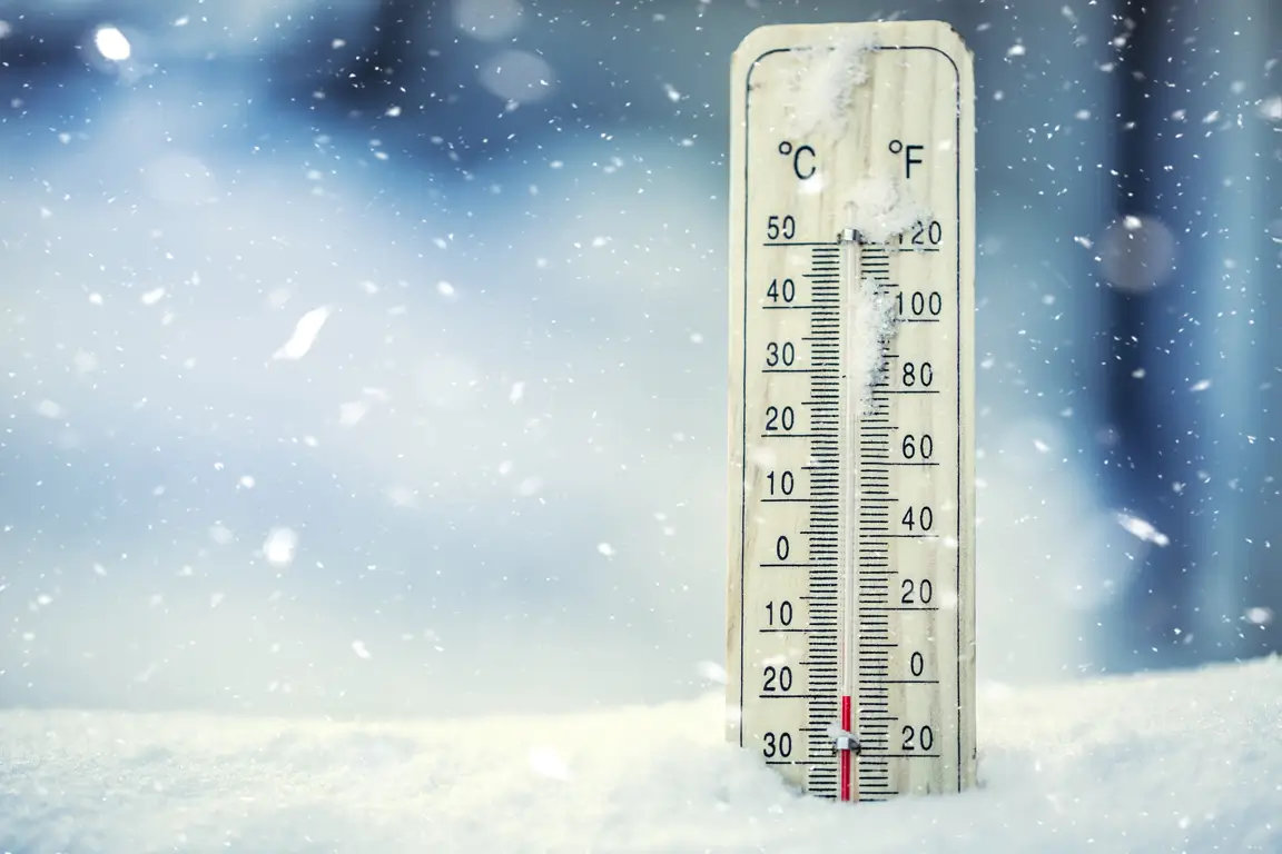 An outdoor thermometer measuring a temperature far below freezing stuck in the snow during a snowfall.