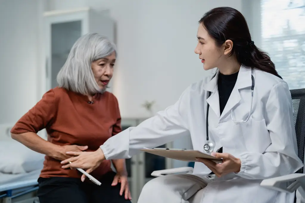 Gastroenterology Physician examining a senior woman's abdomen during a consultation